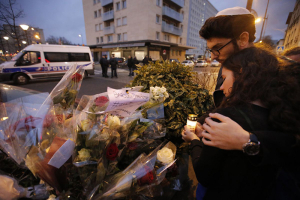 Esther Bekerman, 19, left, a cousin of one of the hostages, and Eliahou Rouas Cohen, 19, right, light a candle at a makeshift memorial near a kosher grocery store where four hostages were killed in Paris, Jan. 10, 2015. Francois Mori—AP <br/>