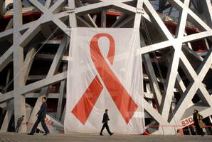 People walk past a giant red ribbon set up on the facade of the Bird's Nest during a World AIDS Day event in Beijing on Sunday. <br/>(Reuters) 