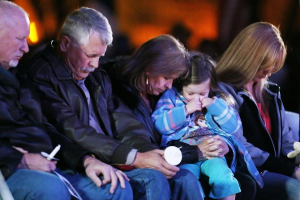 Carl, second from left, and Marsha Mueller, center, bow in prayer at the candlelight memorial in honor of their daughter Kayla Mueller on Wednesday in Prescott, Ariz. Photo: Rob Schumacher/AP <br/>