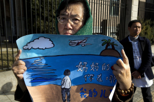 A woman whose son was on board the missing Malaysia Airlines Flight 370 protests with a banner which reads ''Mother's heart is broken, where are you my son'' near the Malaysian Embassy in Beijing on Sunday. Photo: AP <br/>